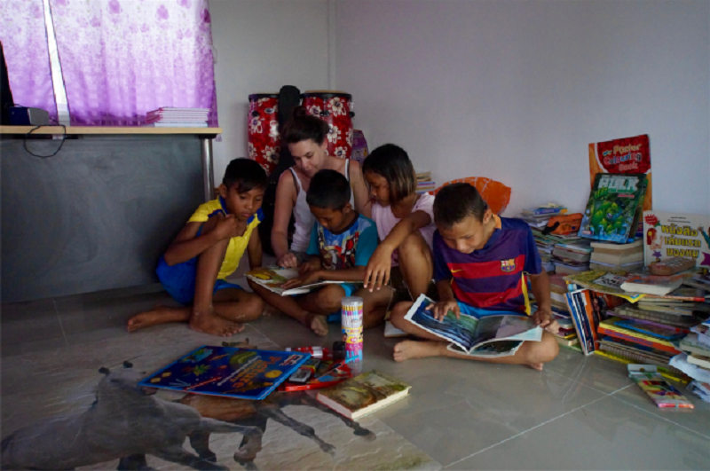 A girl reads book to children